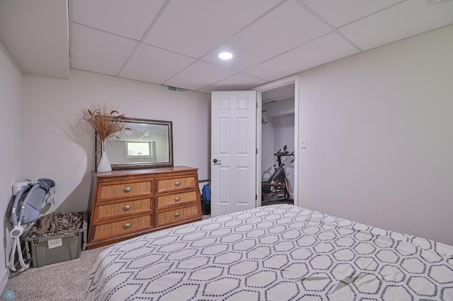 carpeted bedroom featuring a closet and a drop ceiling