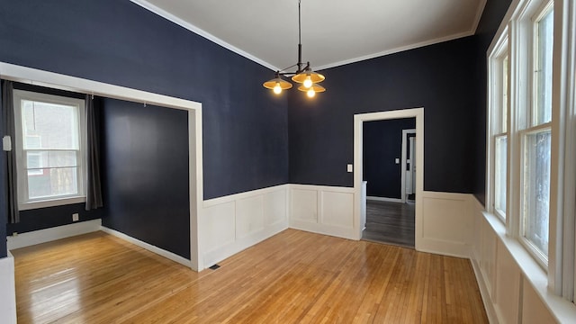 empty room with crown molding, a wealth of natural light, and light hardwood / wood-style flooring