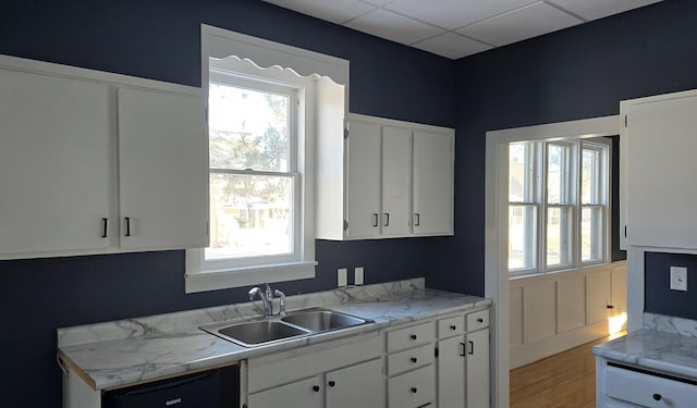 kitchen featuring a drop ceiling, dishwasher, white cabinetry, and sink