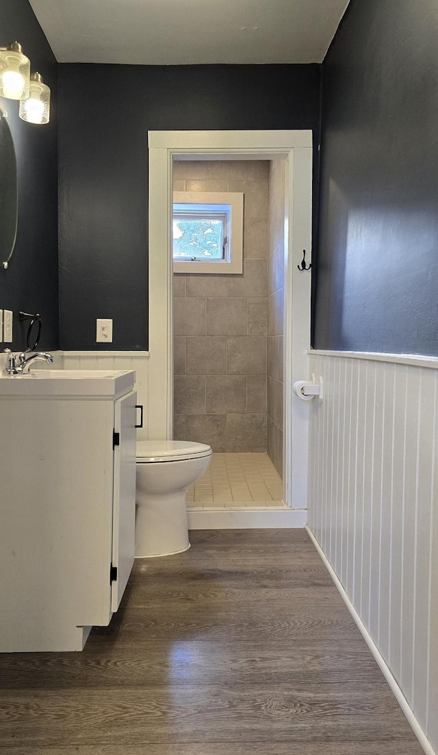 bathroom featuring tiled shower, hardwood / wood-style floors, vanity, and toilet