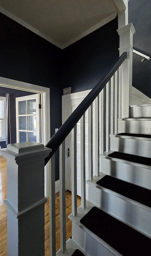 stairway featuring wood-type flooring and ornamental molding