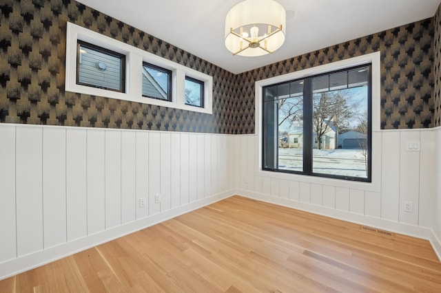 spare room featuring hardwood / wood-style floors, plenty of natural light, and a notable chandelier