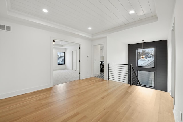 unfurnished room featuring a tray ceiling, hardwood / wood-style floors, and a chandelier