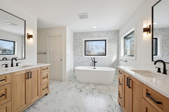 bathroom with a bathing tub, vanity, and a wealth of natural light