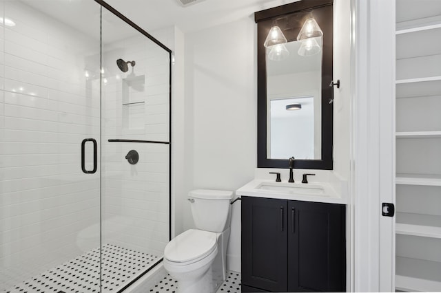 bathroom with tile patterned flooring, vanity, toilet, and a shower with shower door