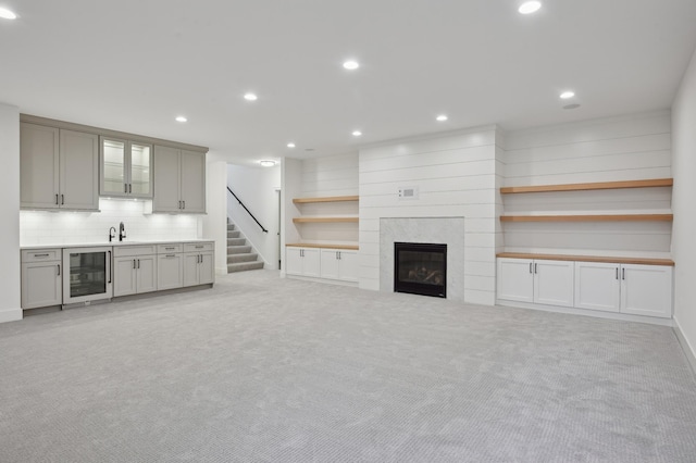 unfurnished living room featuring sink, light colored carpet, and beverage cooler