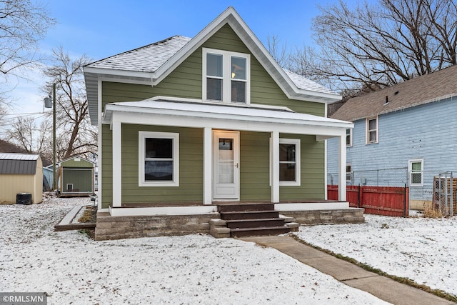 bungalow-style home with a porch and a storage shed