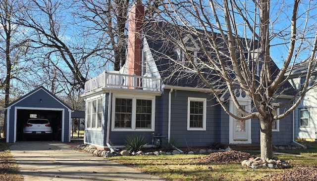 view of home's exterior with a garage, an outdoor structure, and a balcony