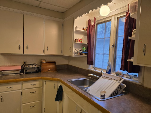 kitchen featuring white cabinets, a drop ceiling, plenty of natural light, and sink