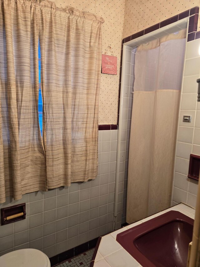 bathroom featuring tile patterned floors, sink, tile walls, and toilet