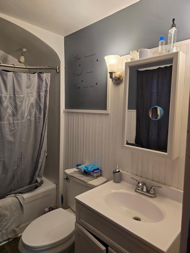 full bathroom featuring shower / bath combo, wood walls, toilet, and vanity