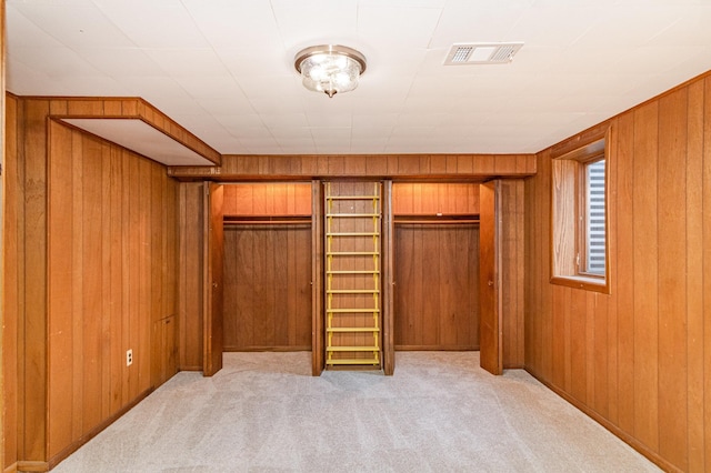 unfurnished bedroom featuring wooden walls, a closet, and light carpet