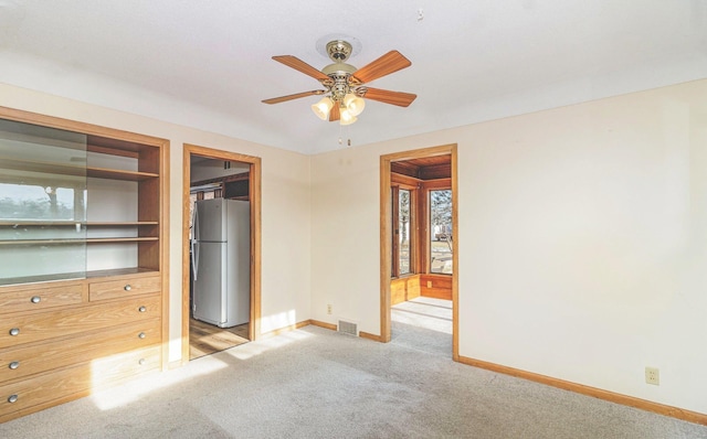 unfurnished bedroom featuring stainless steel fridge, a closet, ceiling fan, and light carpet