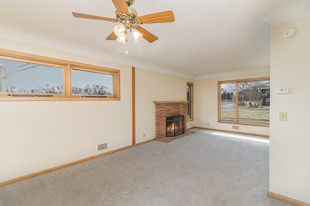 unfurnished living room featuring ceiling fan, carpet floors, and a brick fireplace