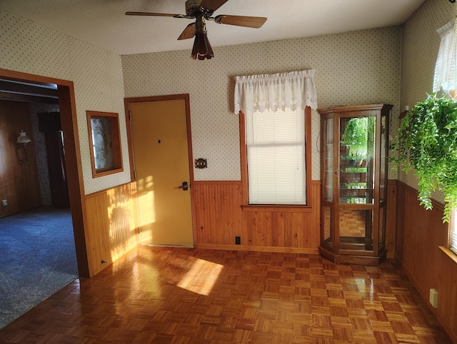 spare room featuring wallpapered walls, a ceiling fan, a wainscoted wall, and a textured ceiling