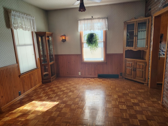 empty room featuring visible vents, wainscoting, wallpapered walls, and wood walls