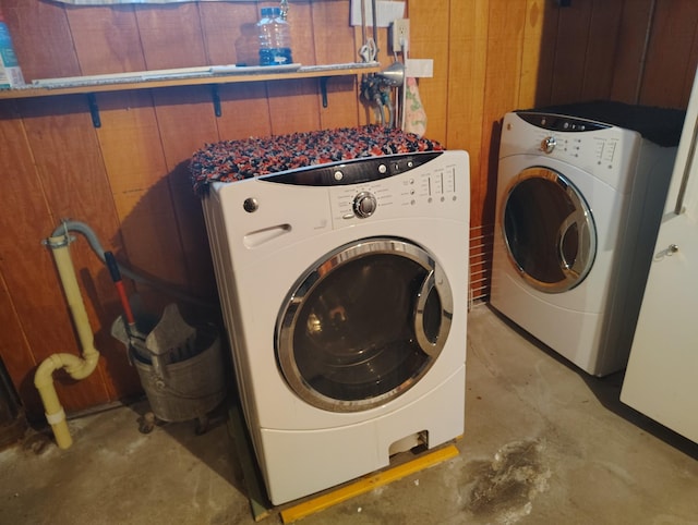 laundry room with washer and clothes dryer and wood walls