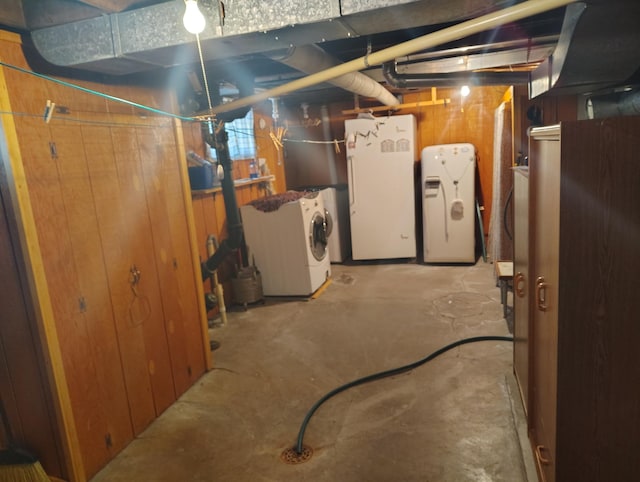 unfinished below grade area with washer and clothes dryer, white refrigerator, and fridge