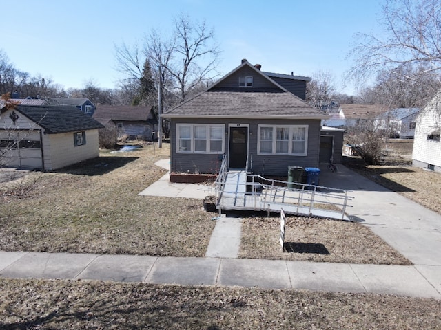 bungalow-style home with a front yard and a shingled roof