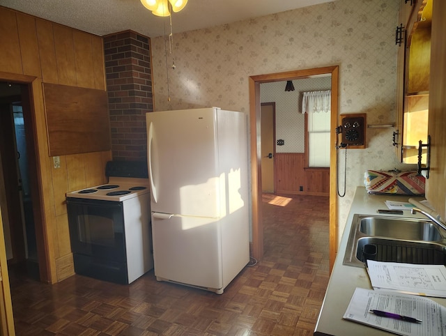 kitchen featuring range with electric cooktop, wallpapered walls, freestanding refrigerator, and a sink