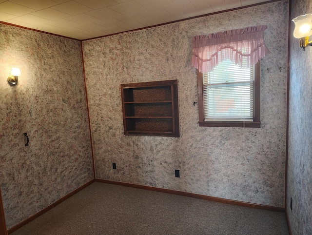 carpeted spare room featuring baseboards and ornamental molding