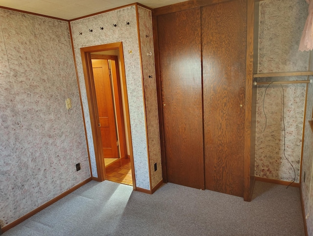 unfurnished bedroom featuring carpet, a closet, and baseboards