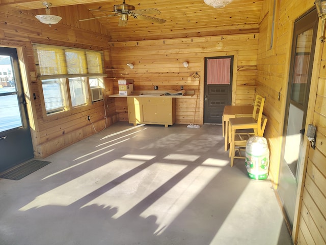 interior space featuring lofted ceiling, wooden walls, cooling unit, and concrete flooring