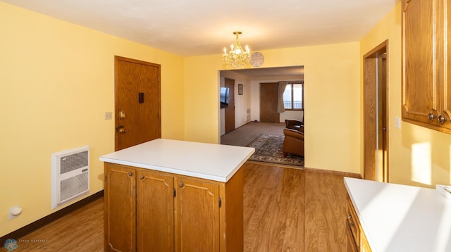 kitchen with heating unit, light hardwood / wood-style flooring, a chandelier, a kitchen island, and hanging light fixtures