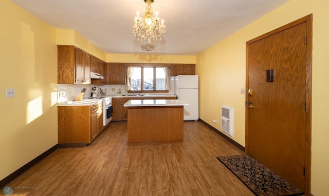 kitchen with hanging light fixtures, a notable chandelier, hardwood / wood-style floors, white appliances, and a kitchen island