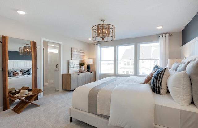 bedroom with light colored carpet, connected bathroom, and an inviting chandelier