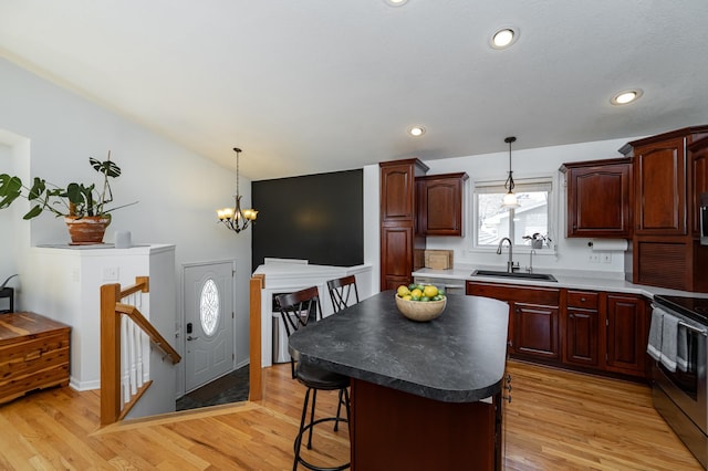 kitchen with light wood-type flooring, a breakfast bar, a sink, a kitchen island, and appliances with stainless steel finishes