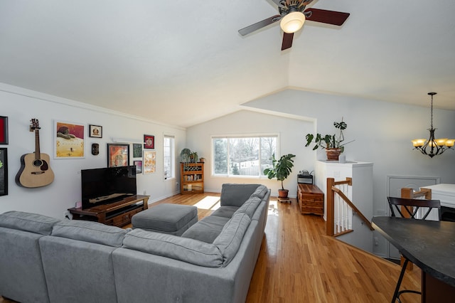 living area featuring ceiling fan with notable chandelier, baseboards, lofted ceiling, and wood finished floors