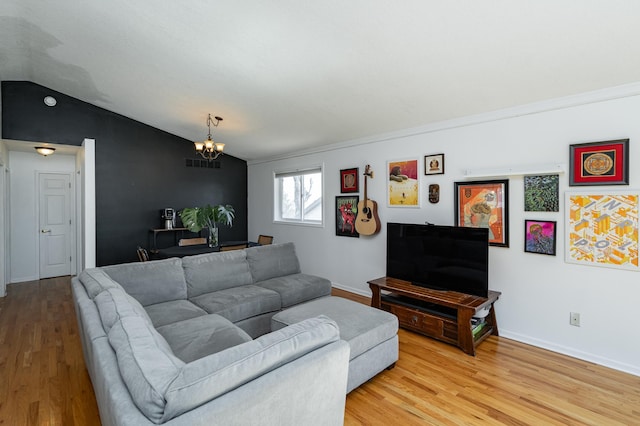 living room featuring a chandelier, baseboards, light wood-type flooring, and lofted ceiling