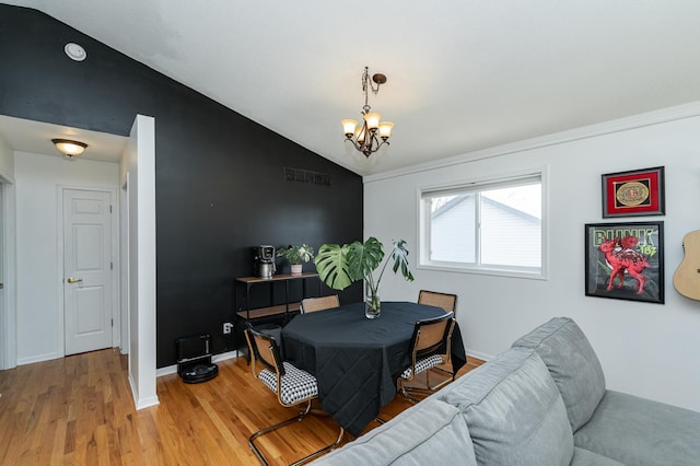 dining space featuring visible vents, light wood-style flooring, baseboards, a chandelier, and vaulted ceiling