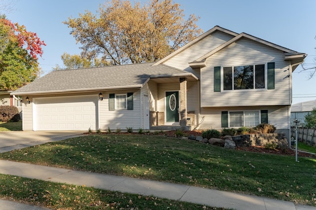 split level home with concrete driveway, an attached garage, and a front yard