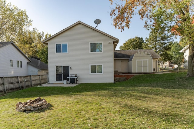 rear view of house featuring an outbuilding, a lawn, fence, a shed, and a patio area