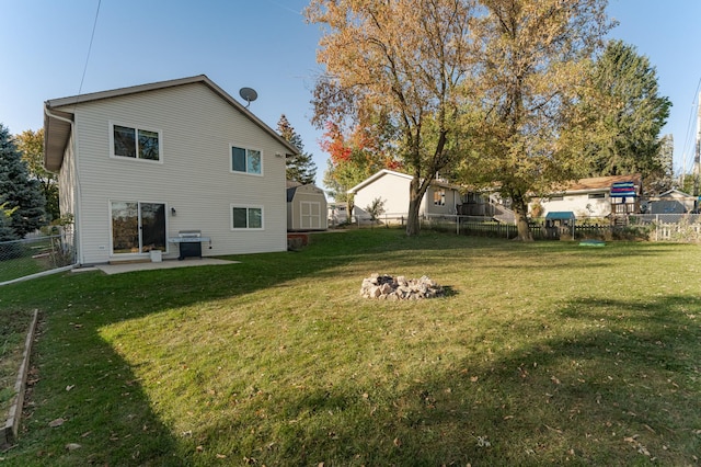 rear view of house with a storage unit, a yard, an outdoor structure, and a fenced backyard