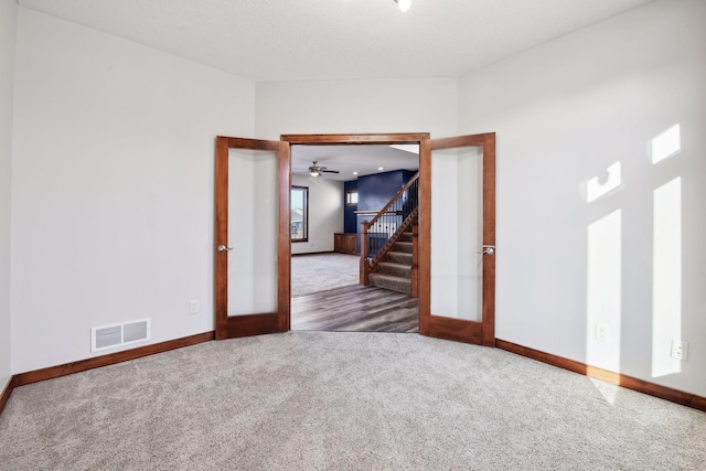 empty room featuring ceiling fan, french doors, and carpet