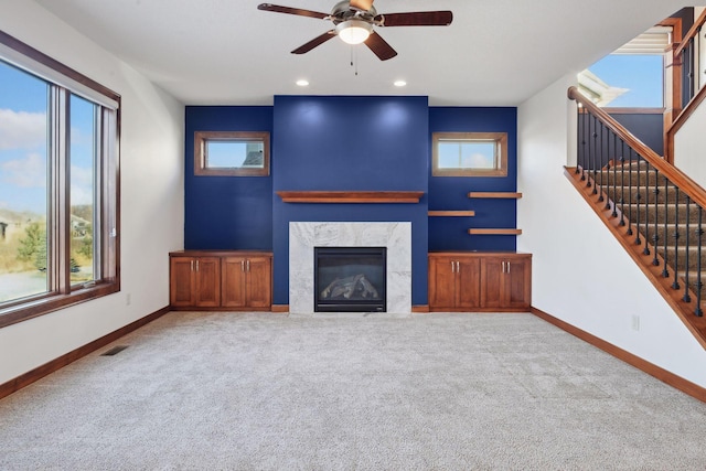 unfurnished living room featuring ceiling fan, a fireplace, carpet, and plenty of natural light