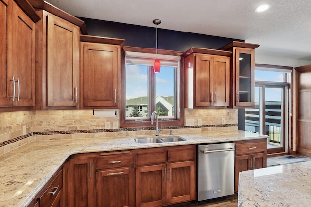 kitchen featuring backsplash, sink, hanging light fixtures, stainless steel dishwasher, and light stone counters