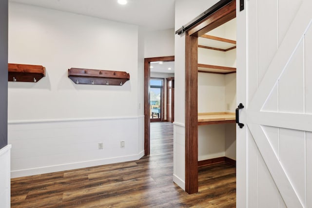 hall with a barn door and dark hardwood / wood-style flooring