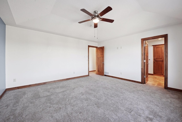 unfurnished bedroom featuring a raised ceiling, ceiling fan, and light colored carpet