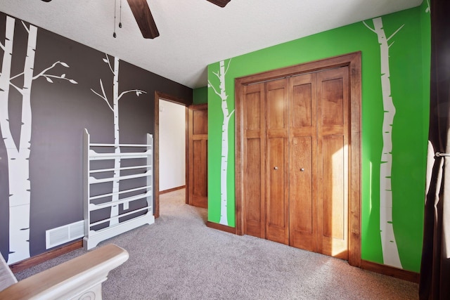 unfurnished bedroom featuring light carpet, a textured ceiling, and ceiling fan