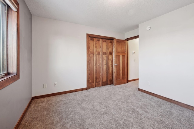 unfurnished bedroom with a textured ceiling, carpet floors, and a closet