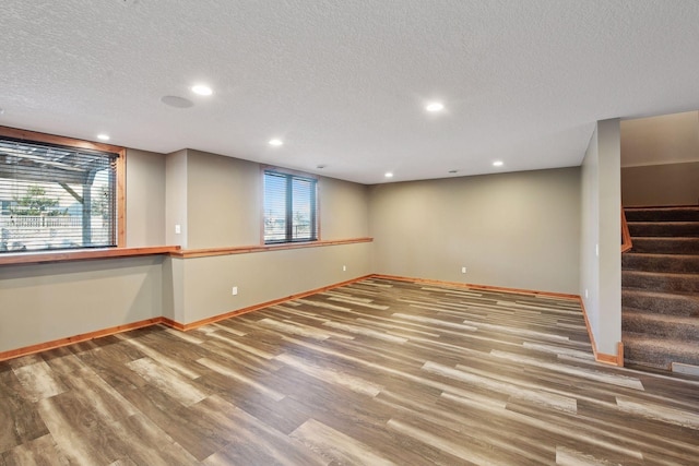 basement with a textured ceiling, hardwood / wood-style floors, and plenty of natural light