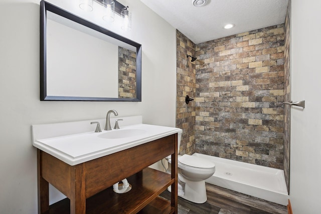 bathroom featuring walk in shower, wood-type flooring, a textured ceiling, toilet, and vanity