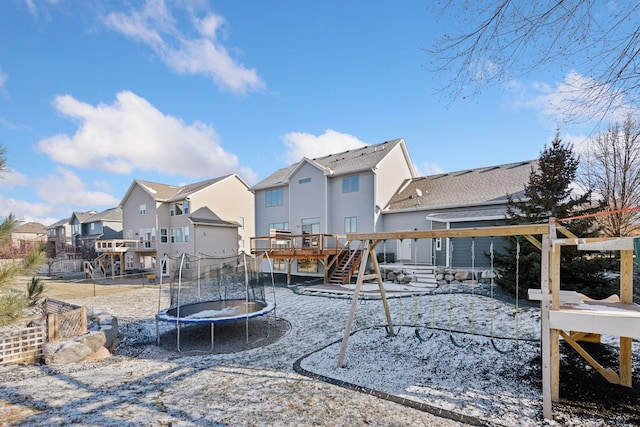 rear view of property with a trampoline and a wooden deck