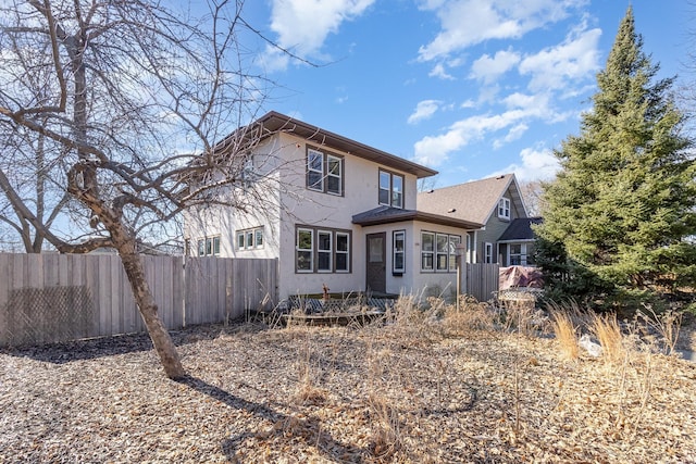 back of property featuring fence and stucco siding