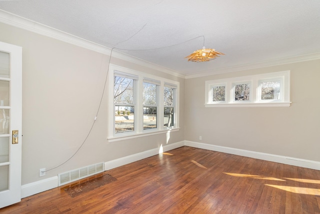 unfurnished room featuring baseboards, hardwood / wood-style floors, visible vents, and crown molding