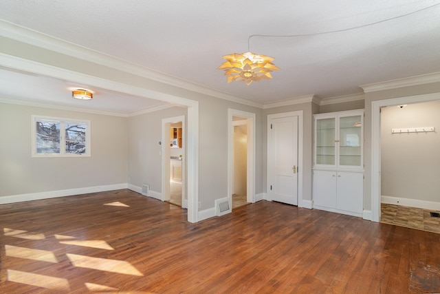 unfurnished room with ornamental molding, wood finished floors, visible vents, and baseboards